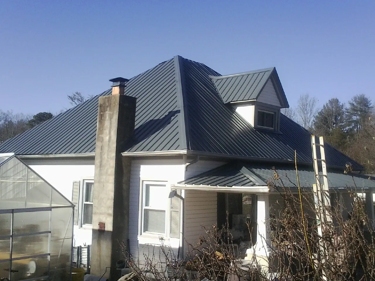 Dark blue standing seam metal roof on a white farmhouse with dormer — Slate & Tile Roof Repair by Roofing Brothers in Selinsgrove