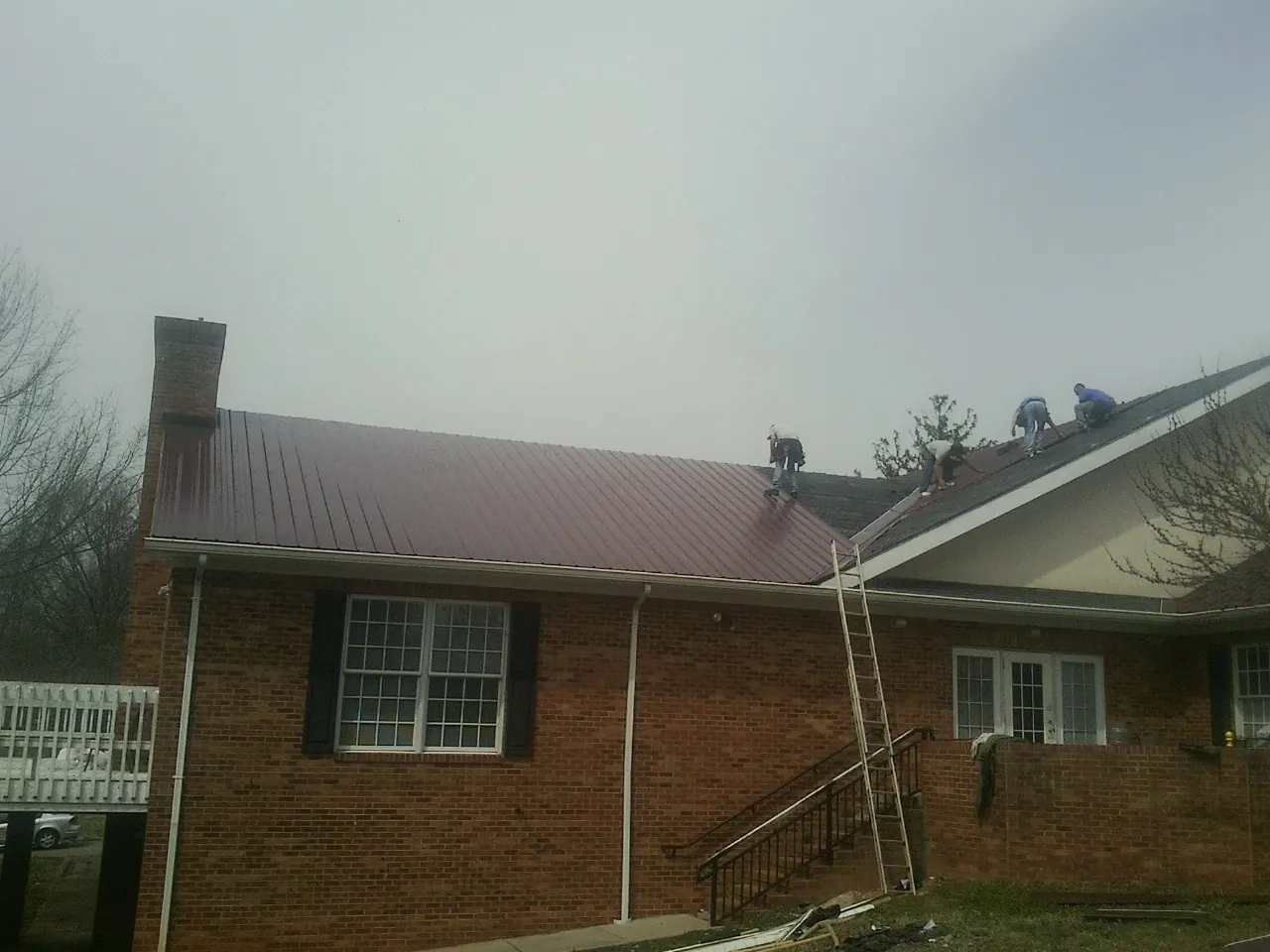 Crew setting red metal roofing panels on a brick home in Selinsgrove