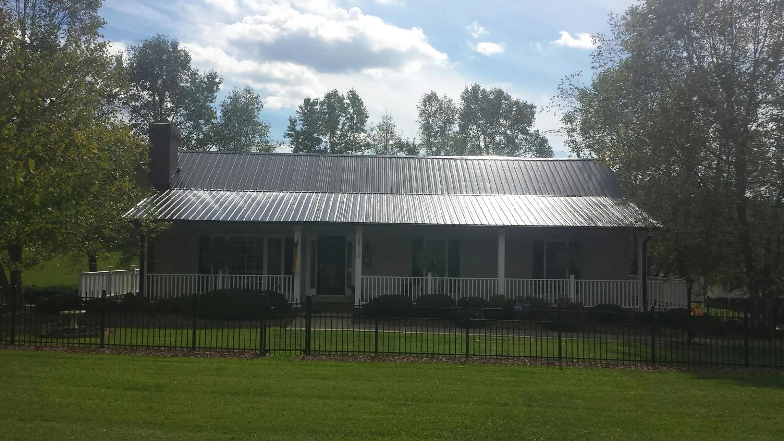 Gray metal roof on a brick ranch with a full width front porch — Gutter Guard Installation work by our crew in Selinsgrove