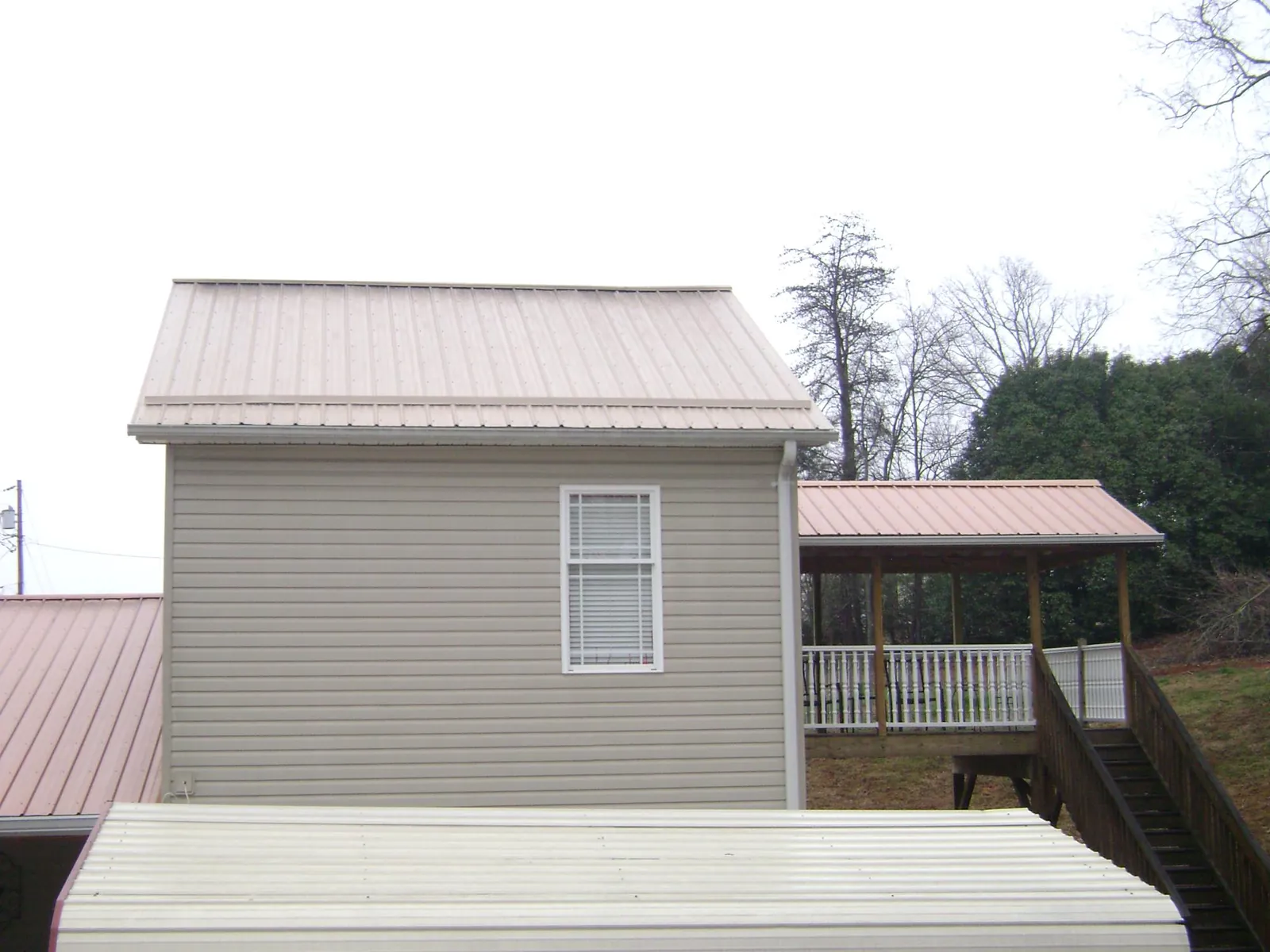 Tan metal roofs on a two story addition and attached porch, from a Roof Replacement job in Selinsgrove