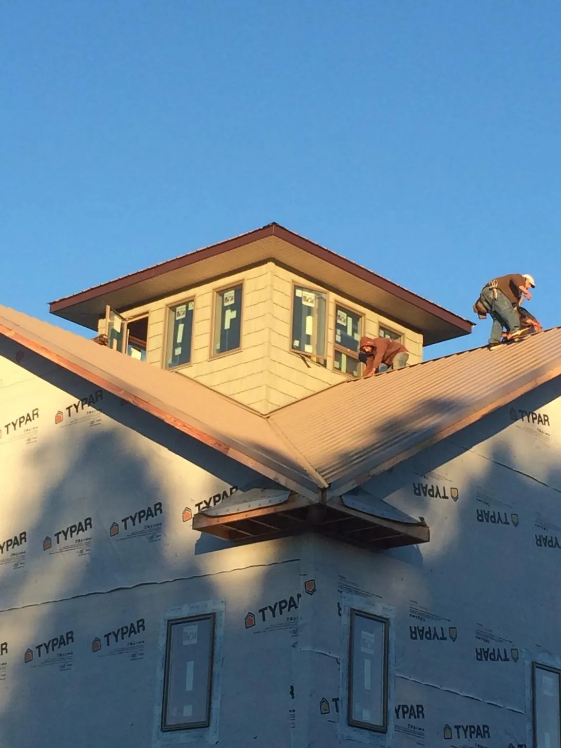 Roofers working around a rooftop cupola on a new metal roof at sunset — Roof Waterproofing in Selinsgrove by Roofing Brothers